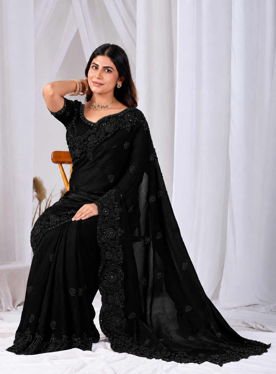 Black Tikki Moti Work Embroidered Designer Saree Black Tikki Moti Work Embroidered Designer Saree + ● The Black Tikki Moti Work Embroidered Designer Saree brings tikki (metallic sequin) and moti (pearl-bead) hand embroidery to a black base, and it's built for anyone comparing options for a black saree rather than something purely decorative. The colour reads true in both daylight and indoor event lighting, which matters more than it sounds &mdash; a lot of sarees photograph differently under venue lighting than they do in a product shot, and this one has been chosen to hold its tone consistently. ● Craftsmanship: The tikki pieces are stitched first to form the outline, then moti beads are layered in to add relief and shine, a slower two-step process than single-technique embroidery. This is what separates a black designer saree from a mass-printed alternative &mdash; the work is done by hand, so no two pieces are perfectly identical, and the detailing holds up to close inspection rather than only looking good from a distance.