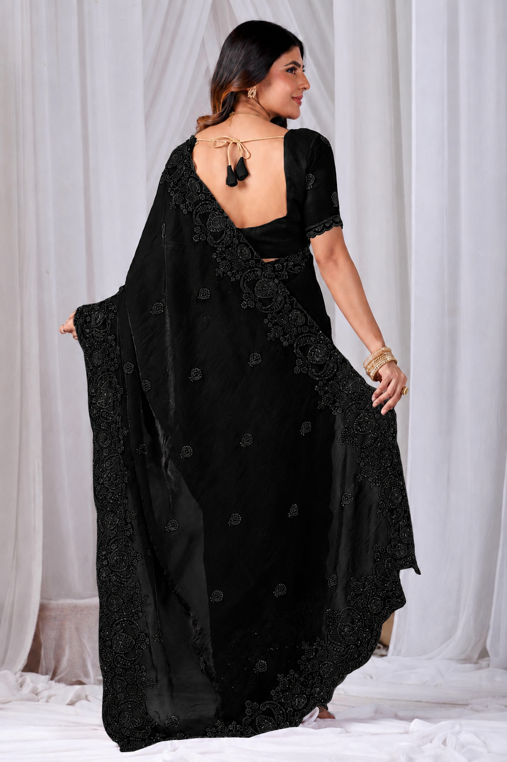 Black Tikki Moti Work Embroidered Designer Saree Black Tikki Moti Work Embroidered Designer Saree + ● The Black Tikki Moti Work Embroidered Designer Saree brings tikki (metallic sequin) and moti (pearl-bead) hand embroidery to a black base, and it's built for anyone comparing options for a black saree rather than something purely decorative. The colour reads true in both daylight and indoor event lighting, which matters more than it sounds &mdash; a lot of sarees photograph differently under venue lighting than they do in a product shot, and this one has been chosen to hold its tone consistently. ● Craftsmanship: The tikki pieces are stitched first to form the outline, then moti beads are layered in to add relief and shine, a slower two-step process than single-technique embroidery. This is what separates a black designer saree from a mass-printed alternative &mdash; the work is done by hand, so no two pieces are perfectly identical, and the detailing holds up to close inspection rather than only looking good from a distance.