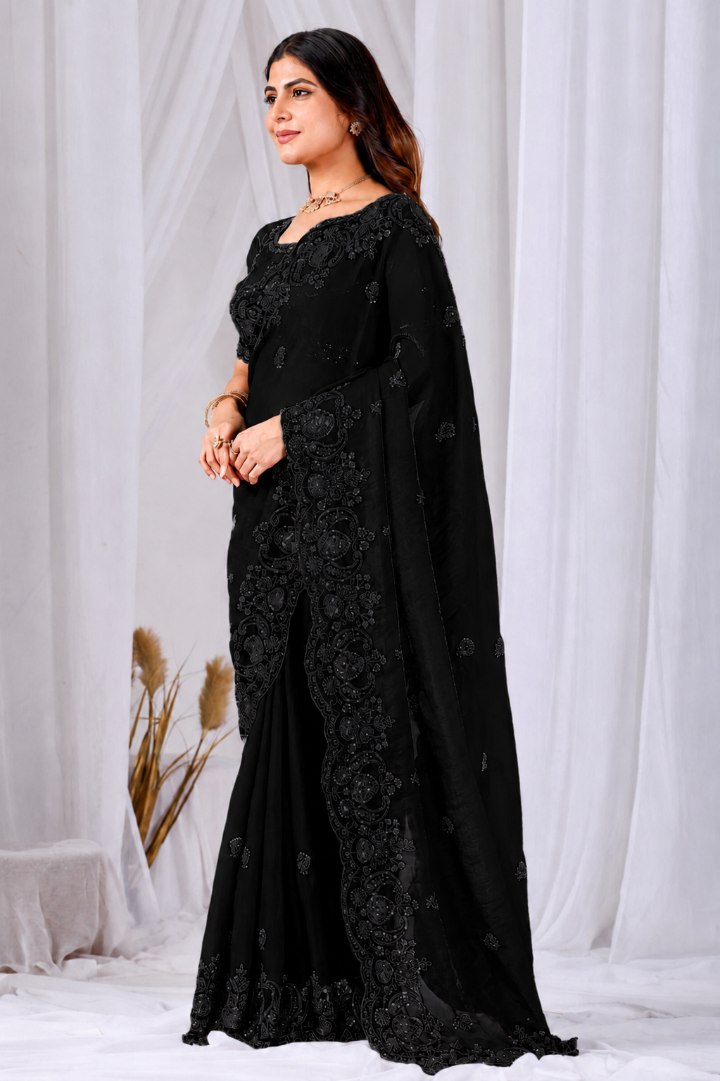 Black Tikki Moti Work Embroidered Designer Saree Black Tikki Moti Work Embroidered Designer Saree + ● The Black Tikki Moti Work Embroidered Designer Saree brings tikki (metallic sequin) and moti (pearl-bead) hand embroidery to a black base, and it's built for anyone comparing options for a black saree rather than something purely decorative. The colour reads true in both daylight and indoor event lighting, which matters more than it sounds &mdash; a lot of sarees photograph differently under venue lighting than they do in a product shot, and this one has been chosen to hold its tone consistently. ● Craftsmanship: The tikki pieces are stitched first to form the outline, then moti beads are layered in to add relief and shine, a slower two-step process than single-technique embroidery. This is what separates a black designer saree from a mass-printed alternative &mdash; the work is done by hand, so no two pieces are perfectly identical, and the detailing holds up to close inspection rather than only looking good from a distance.