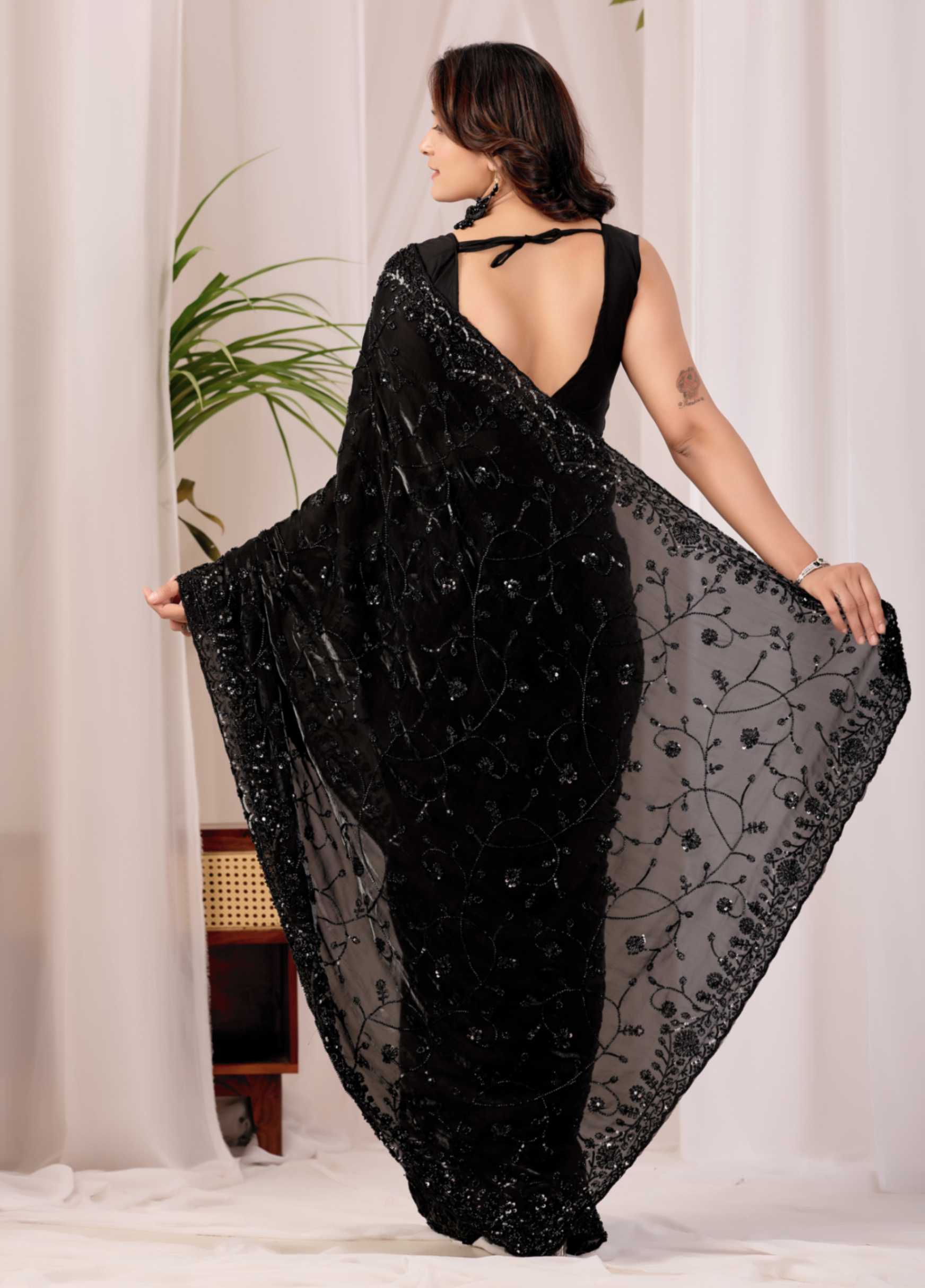 The Black Onyx Sequin Heritage Saree The Black Onyx Sequin Heritage Saree + Embrace the allure of the night with this stunning midnight onyx saree from Kesari Culture. This piece is a masterclass in monochrome elegance, featuring a luxurious black base completely transformed by shimmering tonal sequins. The intricate embroidery creates a subtle yet captivating texture that dances with the light, making it a sophisticated choice for cocktail parties, evening receptions, and high-glamour events. Paired with a sleek, sleeveless V-neck blouse, this ensemble offers a contemporary silhouette while maintaining the timeless grace of traditional attire.